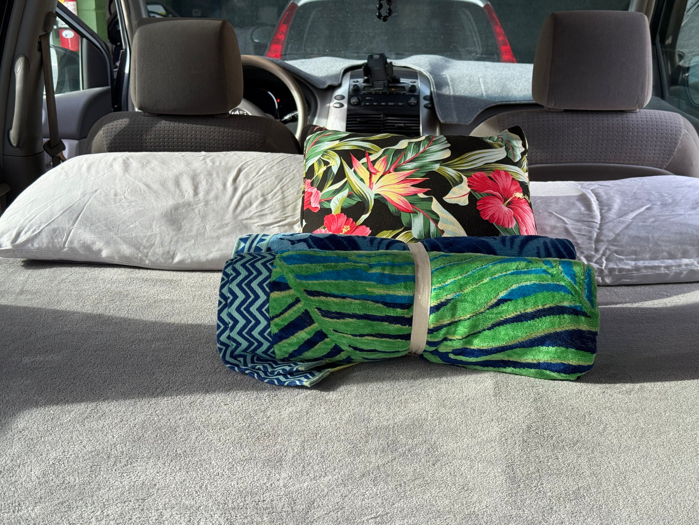 Cozy car setup in an rv rental, with white and floral pillows, plus colorful rolled towels, ready for comfort on a journey.