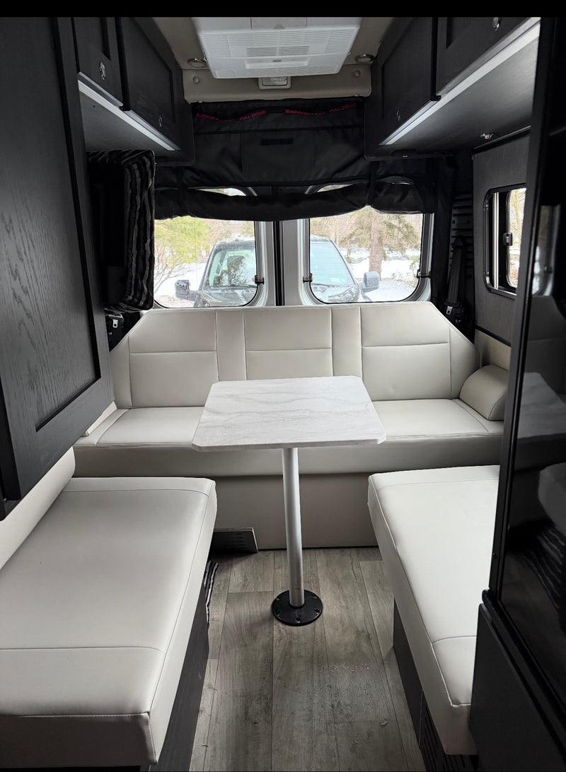 Modern rv rental interior: bright white dinette seating, central table, overhead storage, and rear windows. — photo 6