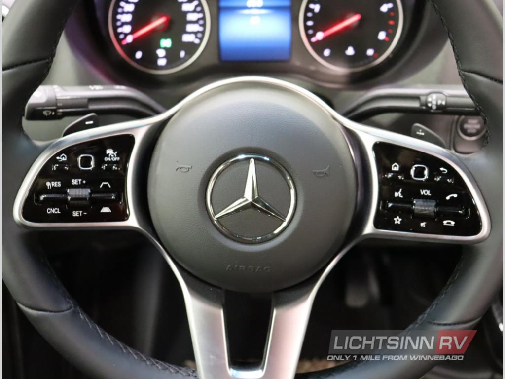 Detailed view of a Mercedes-Benz RV rental steering wheel, featuring adaptive cruise, media, and phone controls.