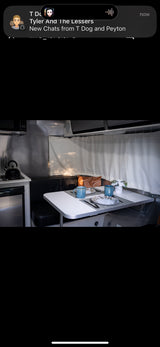 Experience comfort in this RV rental! Interior features a dining area for two, complete kitchen, and sleek metallic walls.