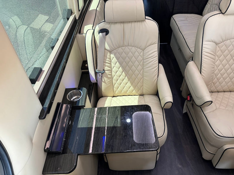 Comfortable RV rental interior showing cream quilted leather captain's chairs, a fold-out table, and a cup holder. — photo 10