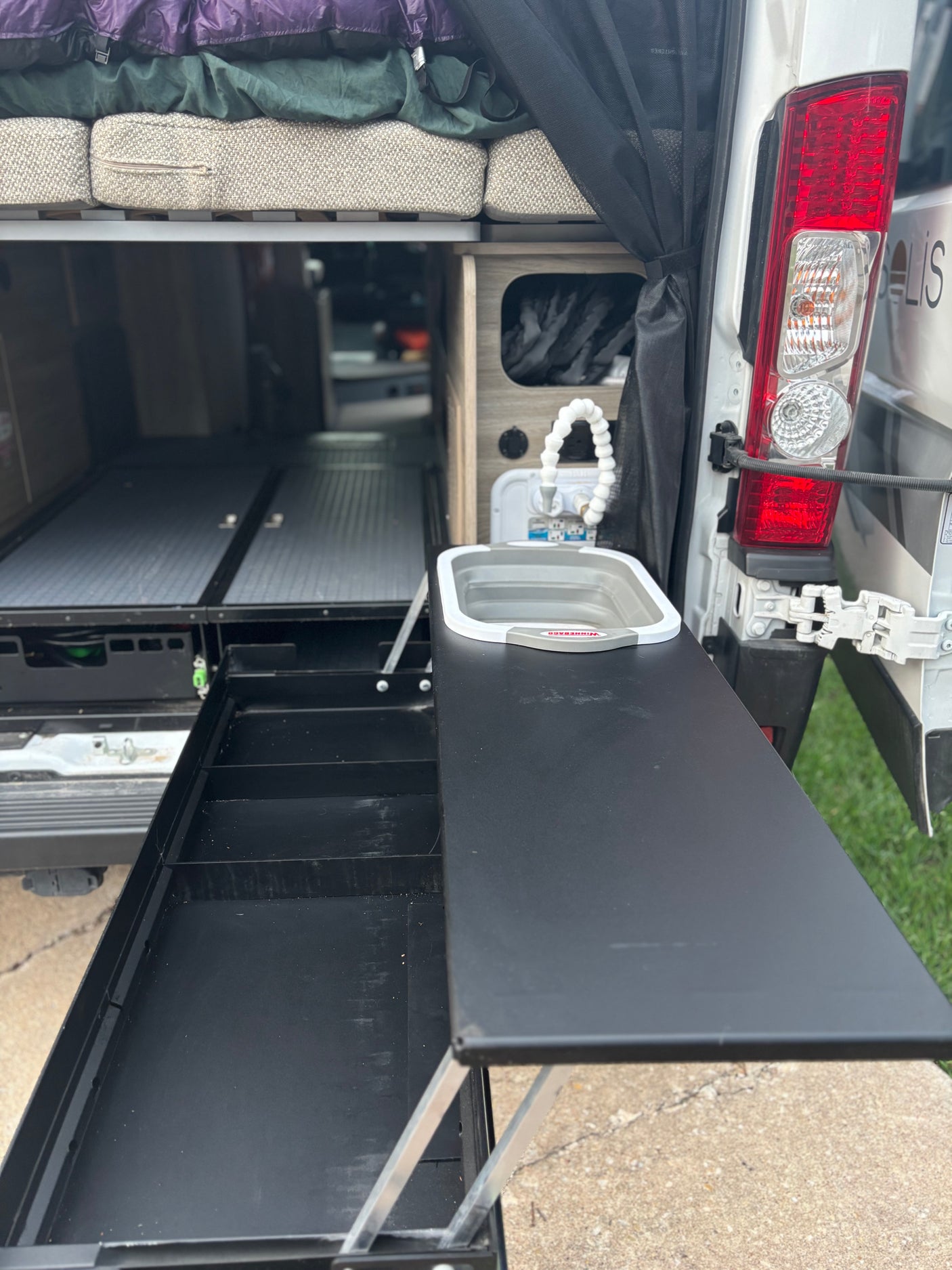 RV rental: Rear access reveals a pull-out outdoor kitchen with collapsible sink, plus generous interior storage/bed space.