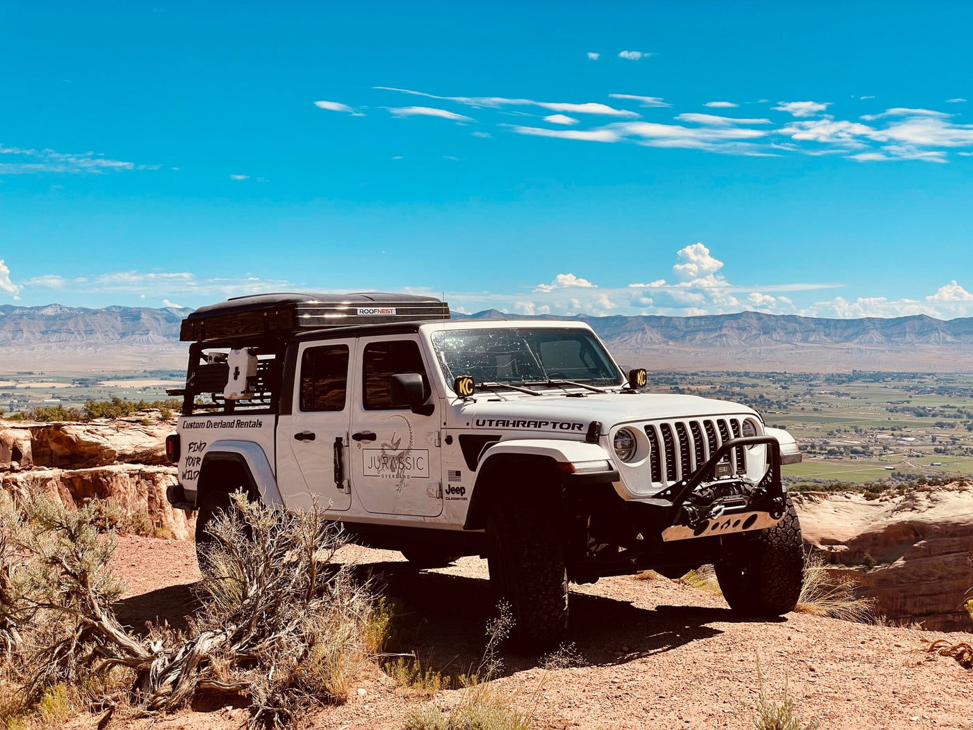  and table set up on a dirt site.|Custom RV rental Jeep Gladiator with rooftop tent ready for overlanding — photo 7