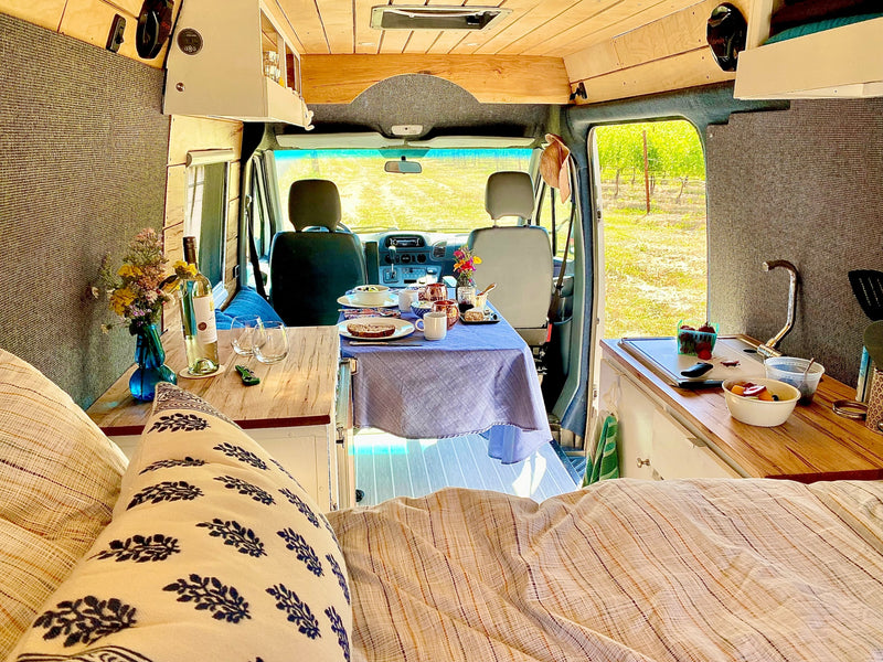 Cozy rv rental interior: dining table set, kitchen, bed, and view to vineyard. Perfect for travel adventures! — photo 3
