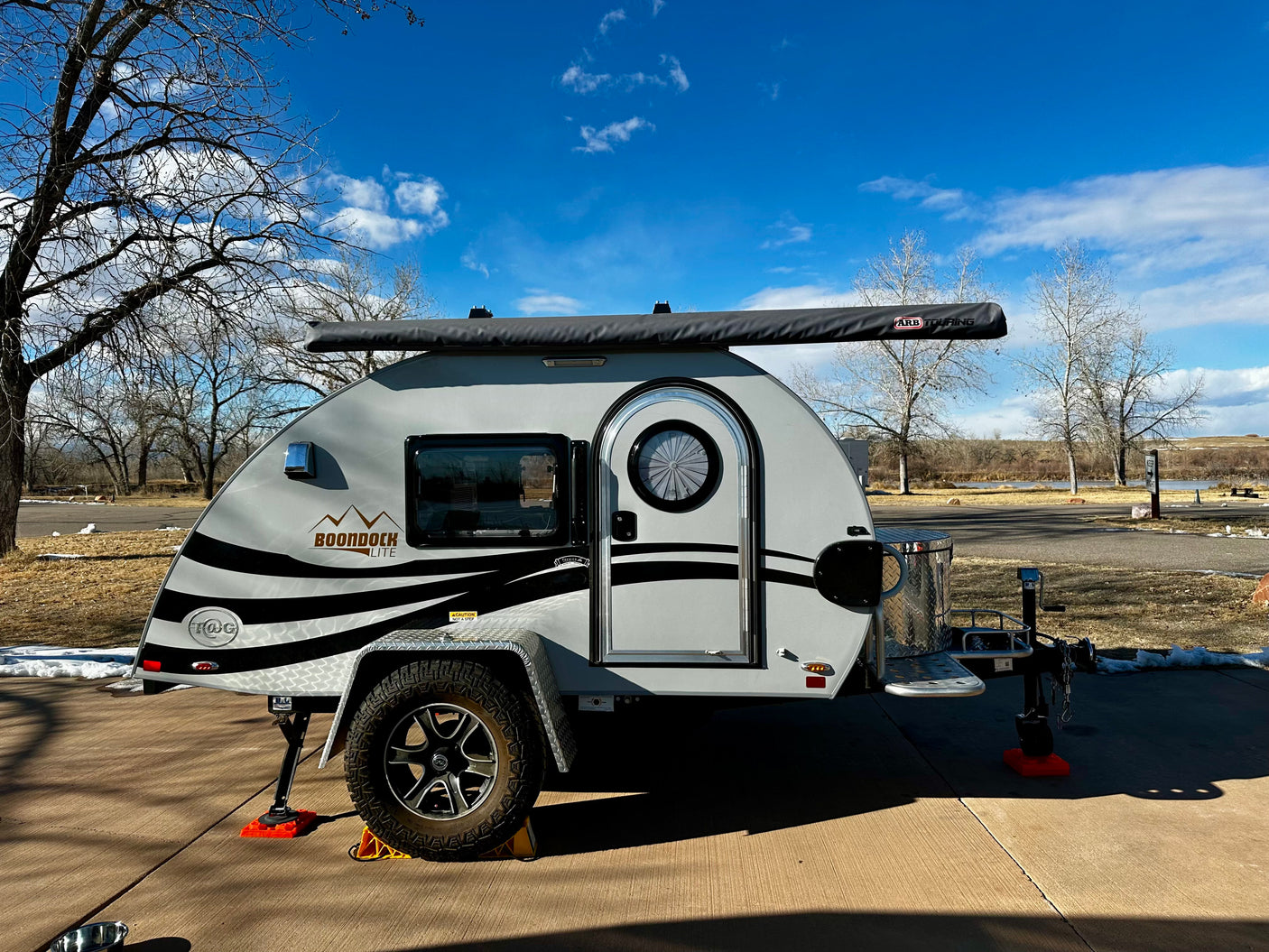 A light gray Boondock Lite teardrop camper with an ARB awning, ideal for your next RV rental adventure.
