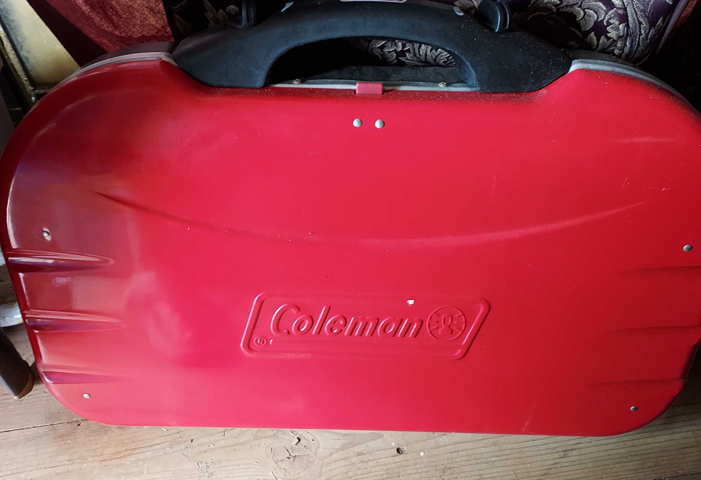 A vibrant red Coleman portable grill, ideal for outdoor cooking during camping trips or your next RV rental.