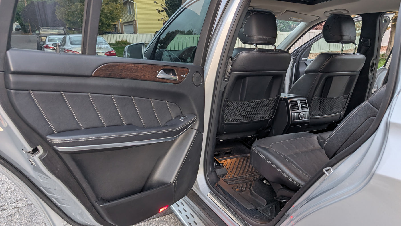 Open rear door of a spacious SUV: black leather seats, wood trim, comfy interior for any journey, including an rv rental trip.