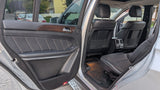 Open rear door of a spacious SUV: black leather seats, wood trim, comfy interior for any journey, including an rv rental trip.