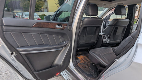 Open rear door of a spacious SUV: black leather seats, wood trim, comfy interior for any journey, including an rv rental trip.