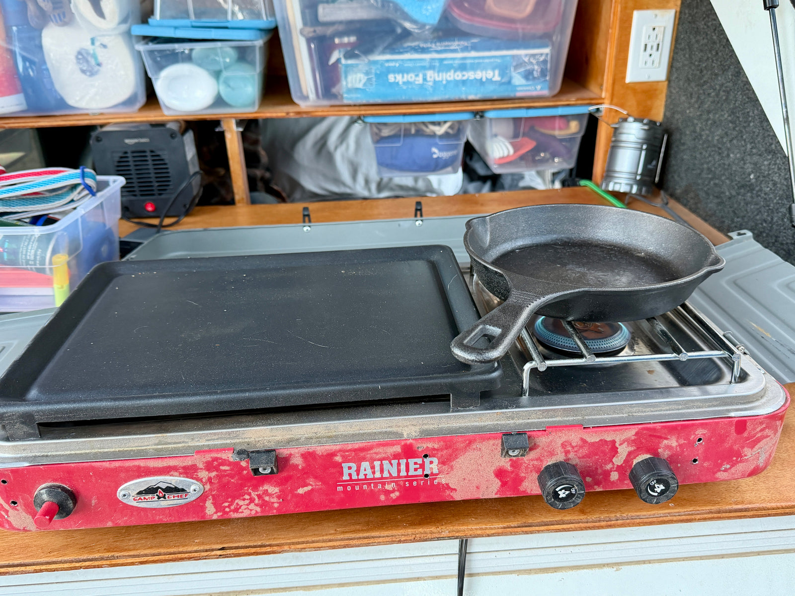**RV rental** kitchen featuring a dusty Camp Chef Rainier stove with a cast iron skillet and griddle for cooking.