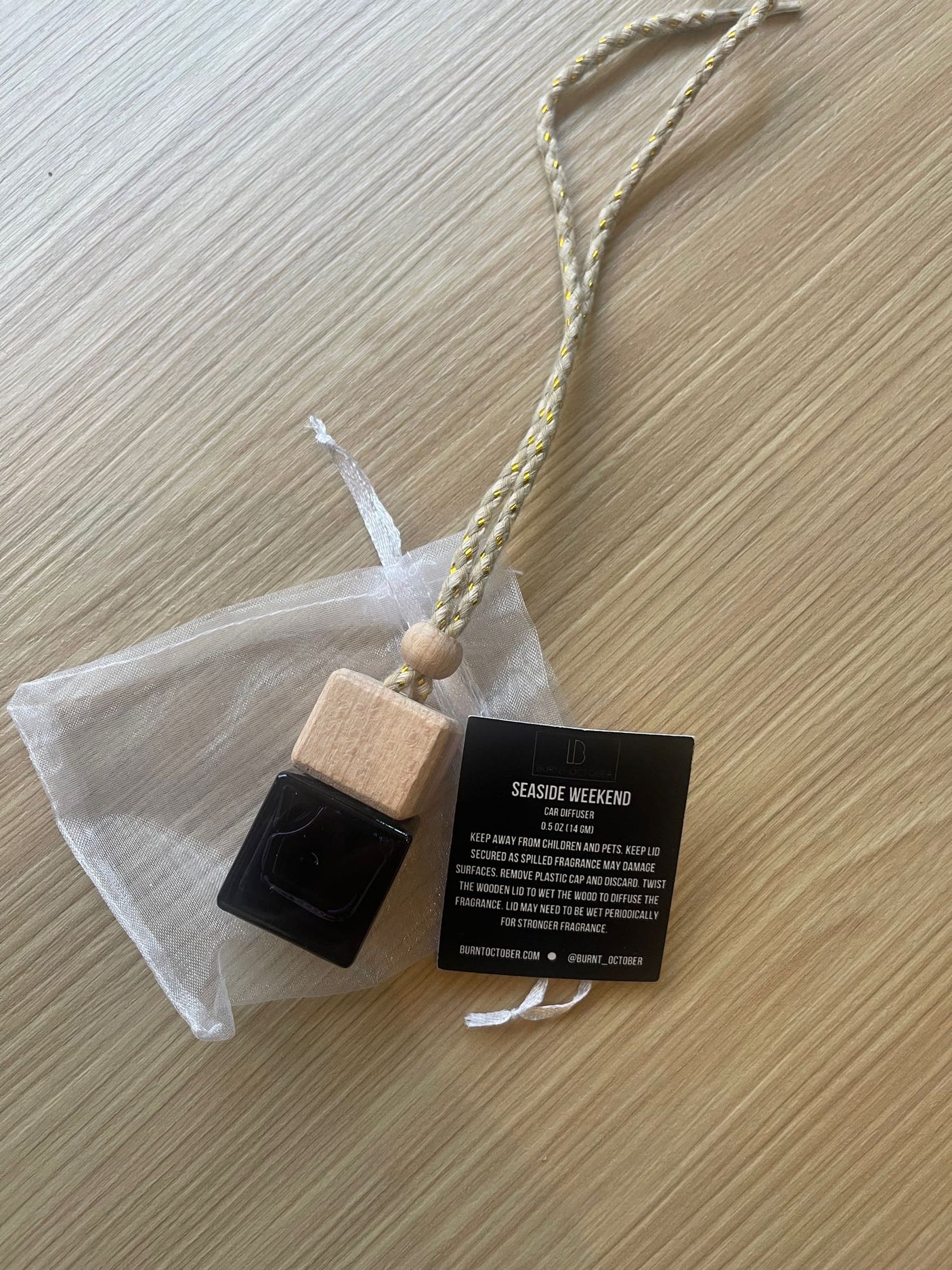 Seaside Weekend car diffuser and info tag in a sheer bag on wood, ideal for your car or an rv rental.