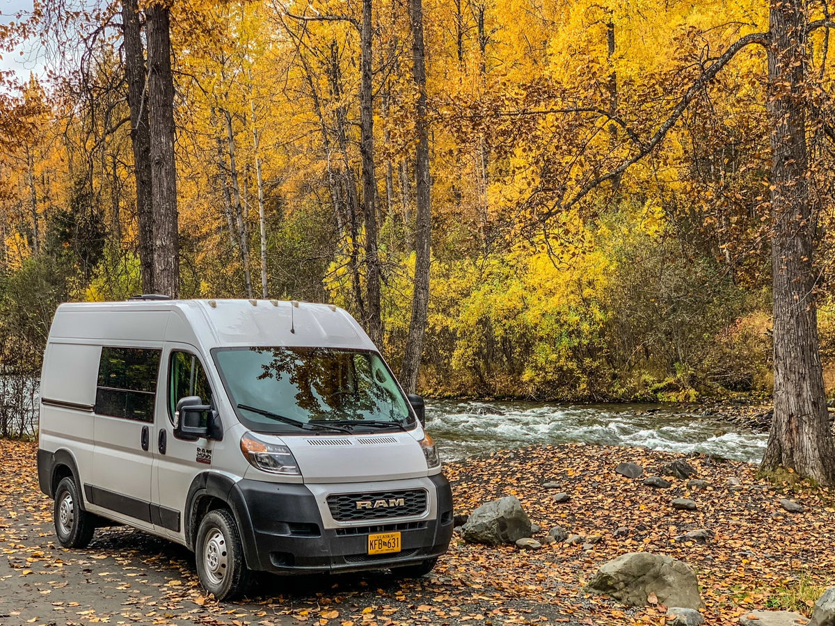 White RV rental parked by a vibrant autumn forest and river. Perfect for scenic fall adventures. — photo 10