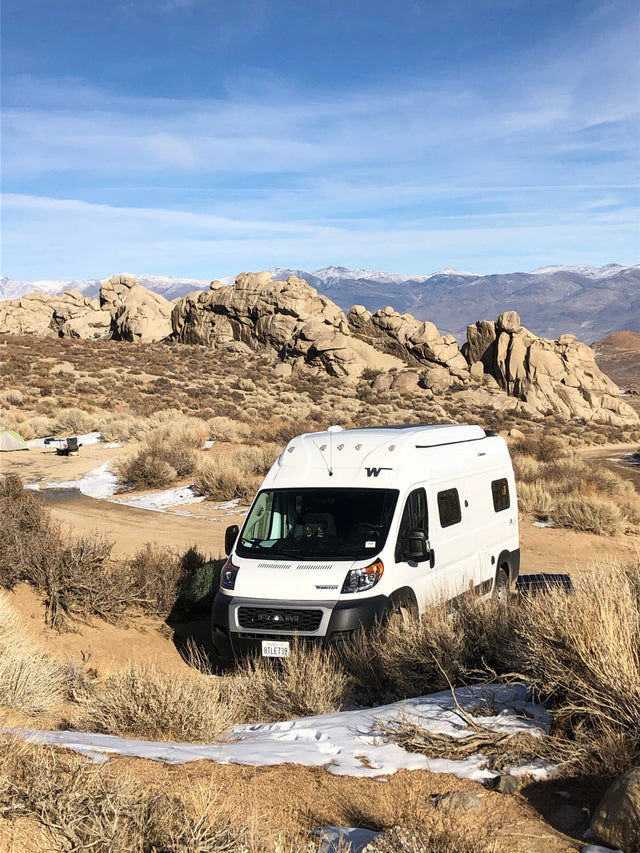 White camper van RV rental in a rugged desert landscape with large rock formations and snow-capped mountains.|Experience winter camping with an rv rental! White camper van amidst a stunning forest of snow-covered trees.|Enjoy winter camping with this RV rental! Snow-covered RVs and snowboards in a picturesque snowy landscape.|Explore this RV rental floorplan