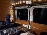 Inside a cozy RV rental: a comfortable sleeping setup with string lights, wooden walls, and a bed.