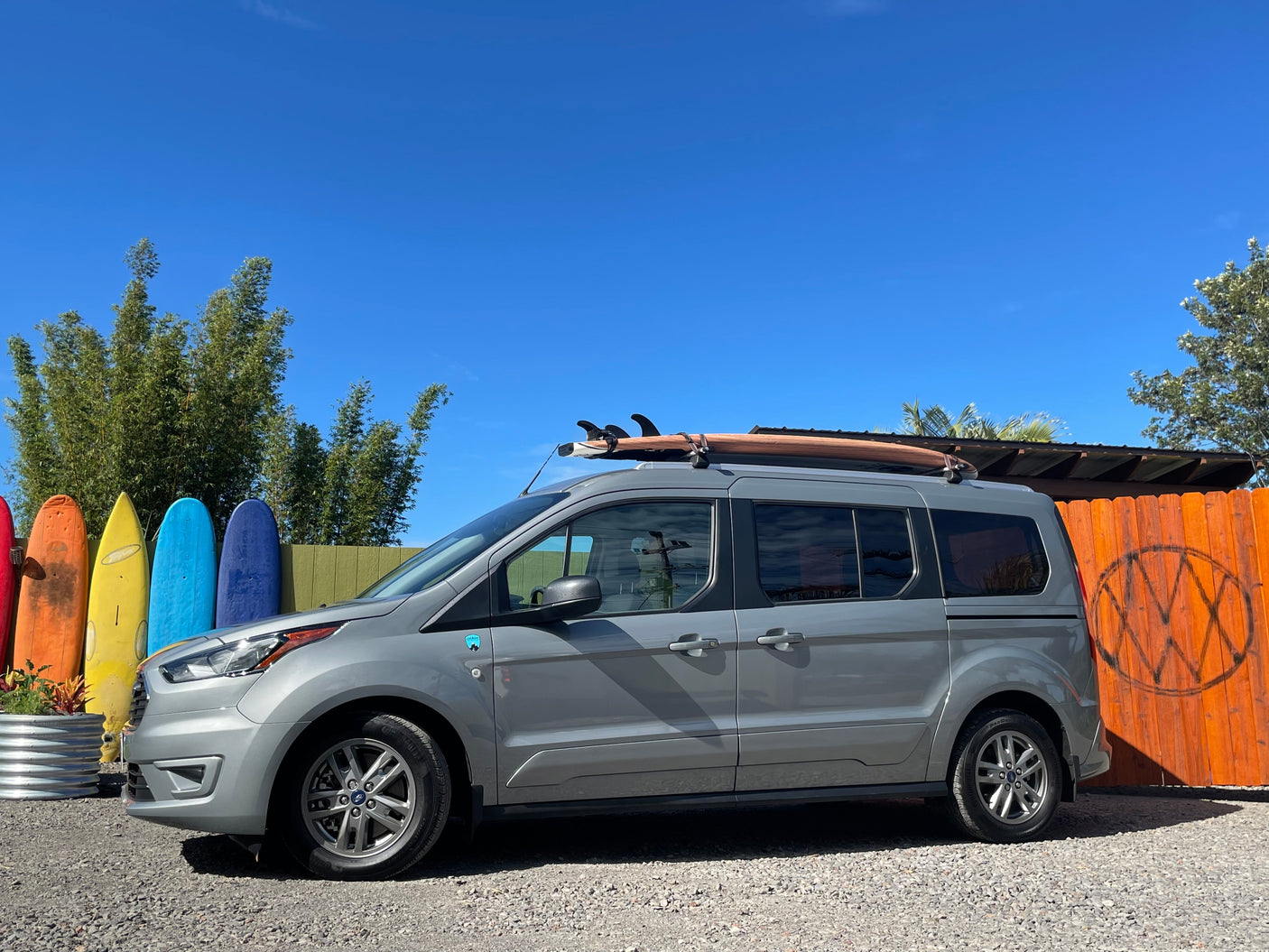 This Ford Transit Connect RV rental, equipped with a surfboard, is ready for beach adventures by colorful boards.