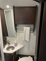 RV rental wet bath with corner sink, mirror, wall cabinet, towel bar, and toilet. Practical, compact design for travel.