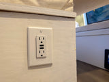 Charging convenience in your RV rental: a white outlet with two USB ports on a light wooden interior wall.