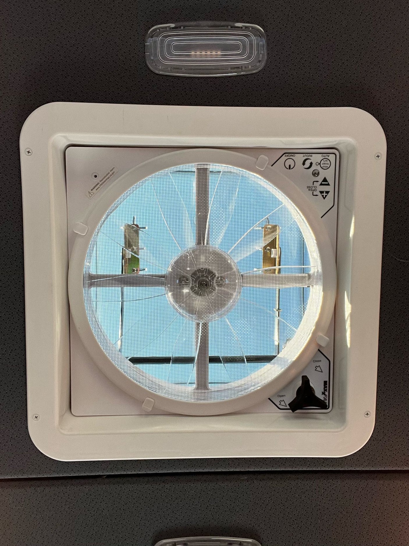 RV rental ceiling fan/vent with screen & controls (on/off, auto, open/close knob), showing a sunny sky.