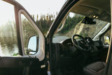 RV rental: View from inside a camper van, driver's door open to a lake and winding mountain road.