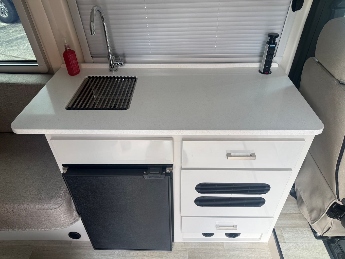 Efficient RV rental kitchen featuring a white countertop, sink, NOVAKOOL fridge, and a pop-up power station for your journey. — photo 4