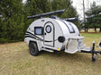 This compact teardrop travel trailer, ideal for rv rental, features a unique round door, roof awning, and front storage box.