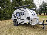This compact teardrop travel trailer, ideal for rv rental, features a unique round door, roof awning, and front storage box.