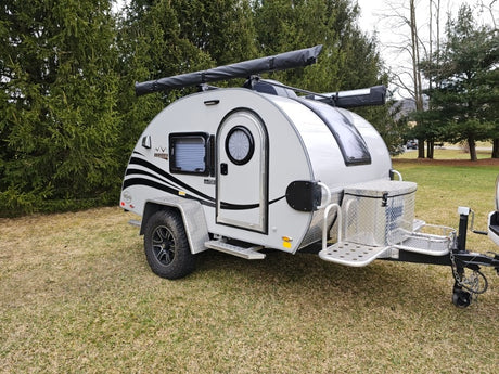 This compact teardrop travel trailer, ideal for rv rental, features a unique round door, roof awning, and front storage box.