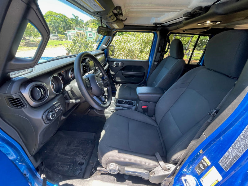 Blue Jeep interior, likely for an RV rental. View from driver's seat shows dashboard, seats, and lush outdoor scenery. — photo 12
