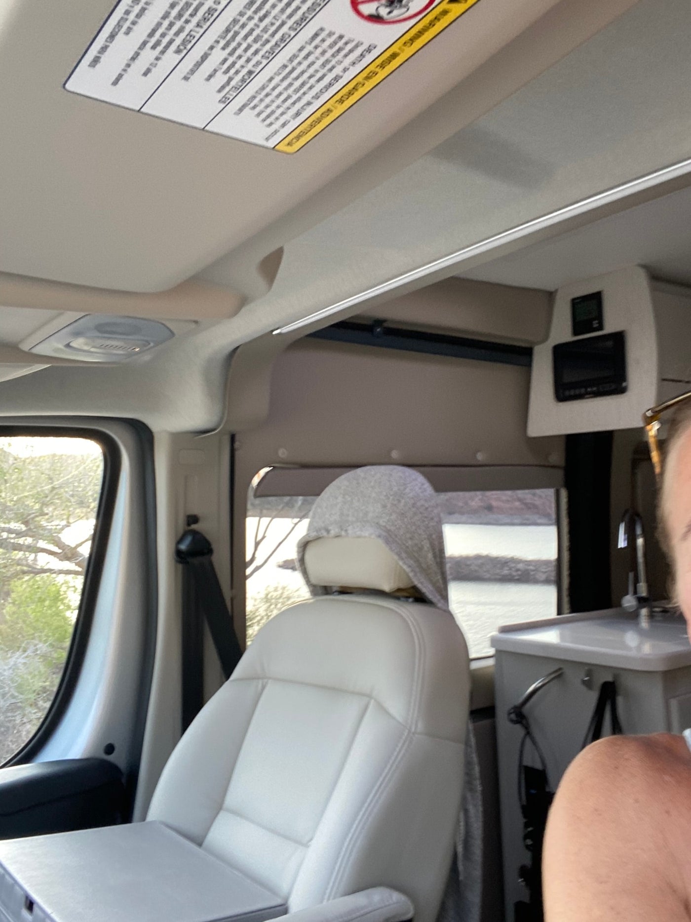 Cozy RV rental interior with a passenger seat, a glimpse of the mobile kitchen, and a beautiful lake view outside. — photo 14