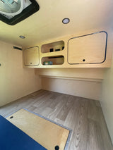 Clean and bright RV rental interior showcasing light wood paneling, built-in storage, and modern wood-look flooring.