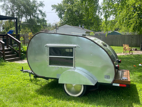 Classic silver teardrop travel trailer, perfect for your next rv rental adventure, parked in a sunny backyard.