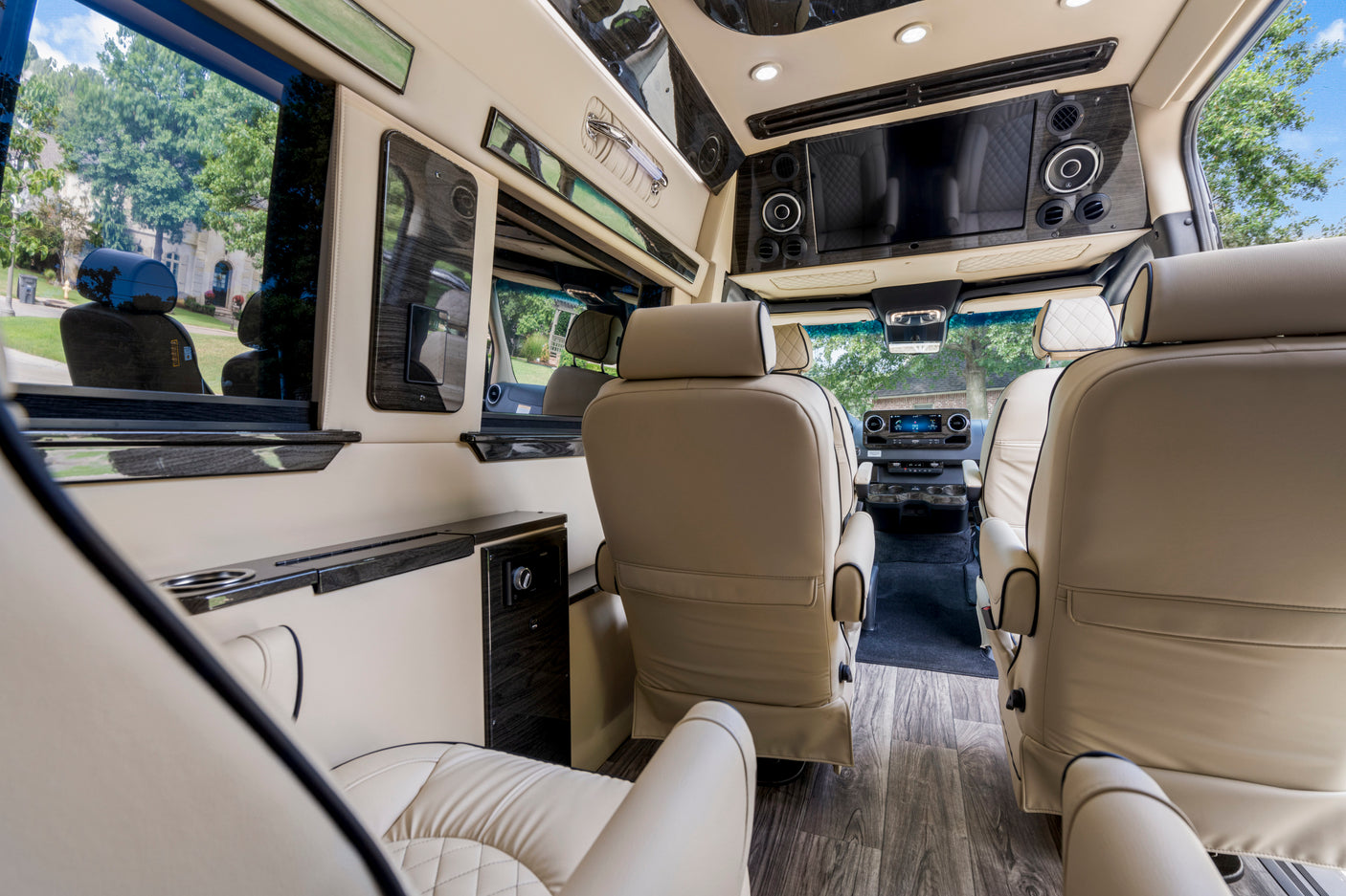 The lavish interior of an RV rental, showcasing cream-colored leather seats, wood-grain details, and an entertainment screen.
