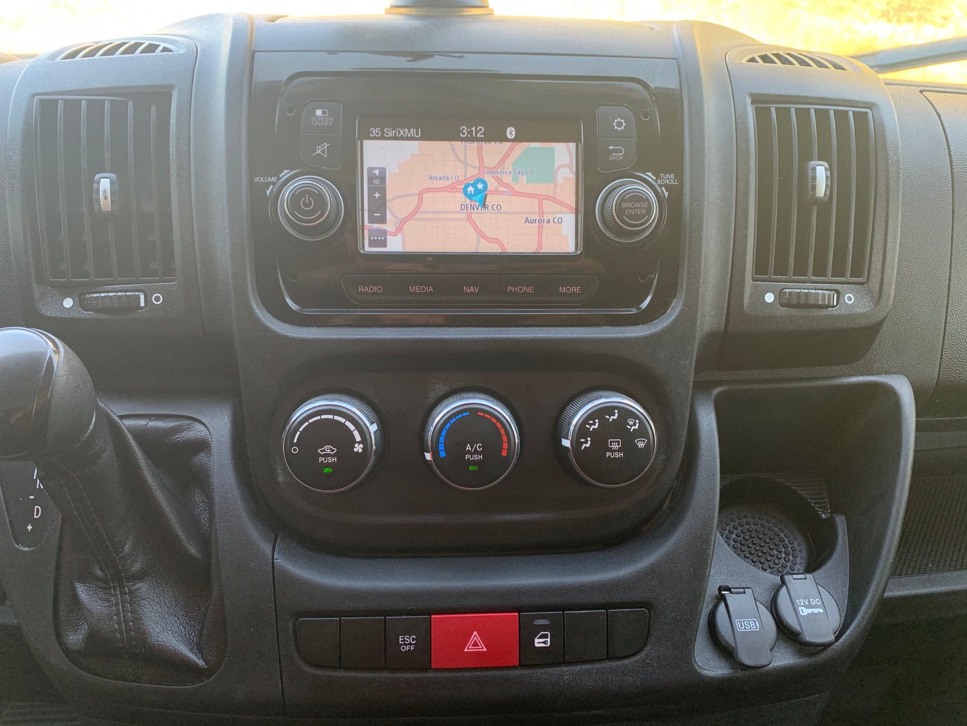 Inside an RV rental: a detailed dashboard with an active navigation screen showing Denver and accessible climate controls.