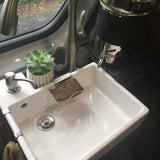 Bright sink with soap, sponge, and plant in an RV rental. Modern faucet and compact design for on-the-go living.