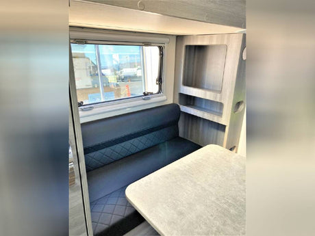Spacious RV rental interior featuring a comfortable dinette with bench seating, a table, and convenient built-in shelving.
