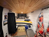 Step inside this cozy RV rental's custom interior! Features a comfy bed, smart storage, and stylish decor for van life.