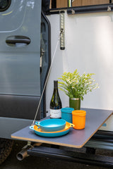 This RV rental features a handy pop-out table for outdoor meals, complete with wine, flowers, and colorful camp kitchenware.