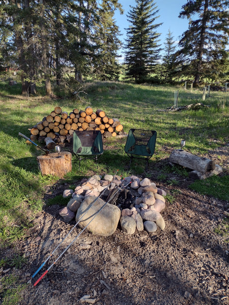 Perfect RV rental campsite with chairs, stacked firewood, and a stone campfire pit for outdoor evenings.