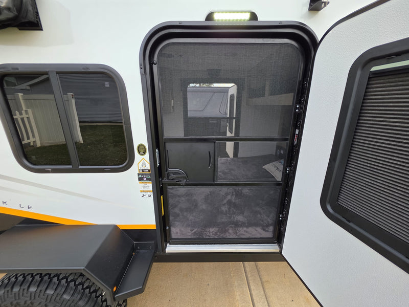 RV rental: side view of a white camper with open black screen door, closed main entry door, and window. Shows tire/fender. — photo 10