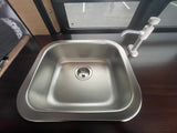 **RV rental** kitchen amenities: a stainless steel **sink** with pump **faucet** on a dark countertop. A window shows the outside.