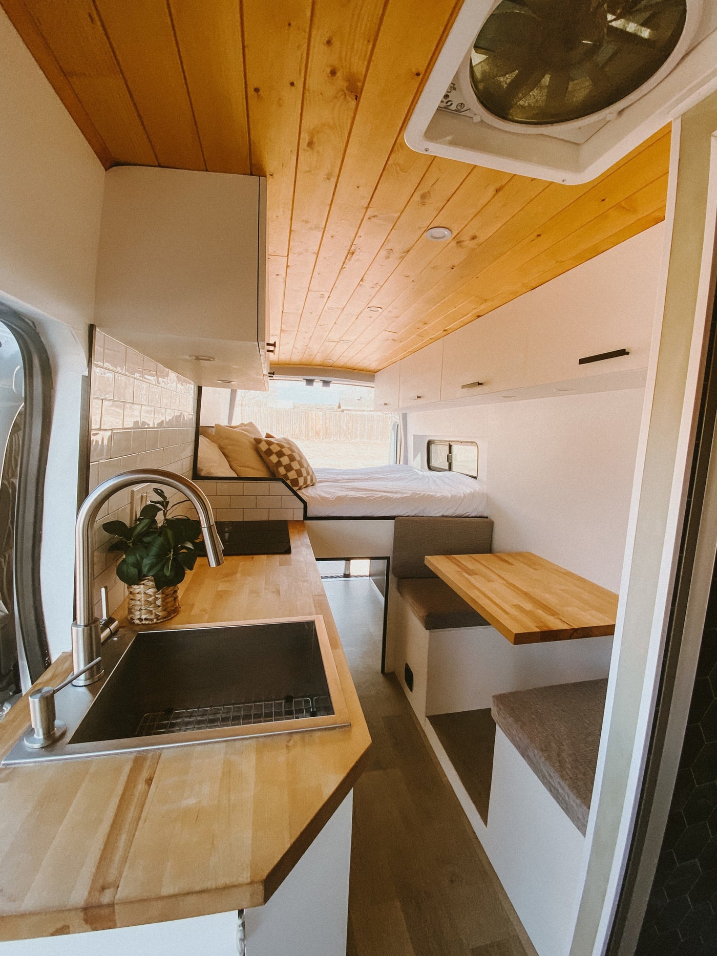 Modern camper van RV rental interior: bright kitchen, cozy bed, and dining space with wood accents. Your adventure awaits! — photo 8