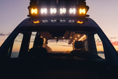 Experience a vibrant sunset from an **rv rental** van, showcasing its bright roof lights and comfortable interior.