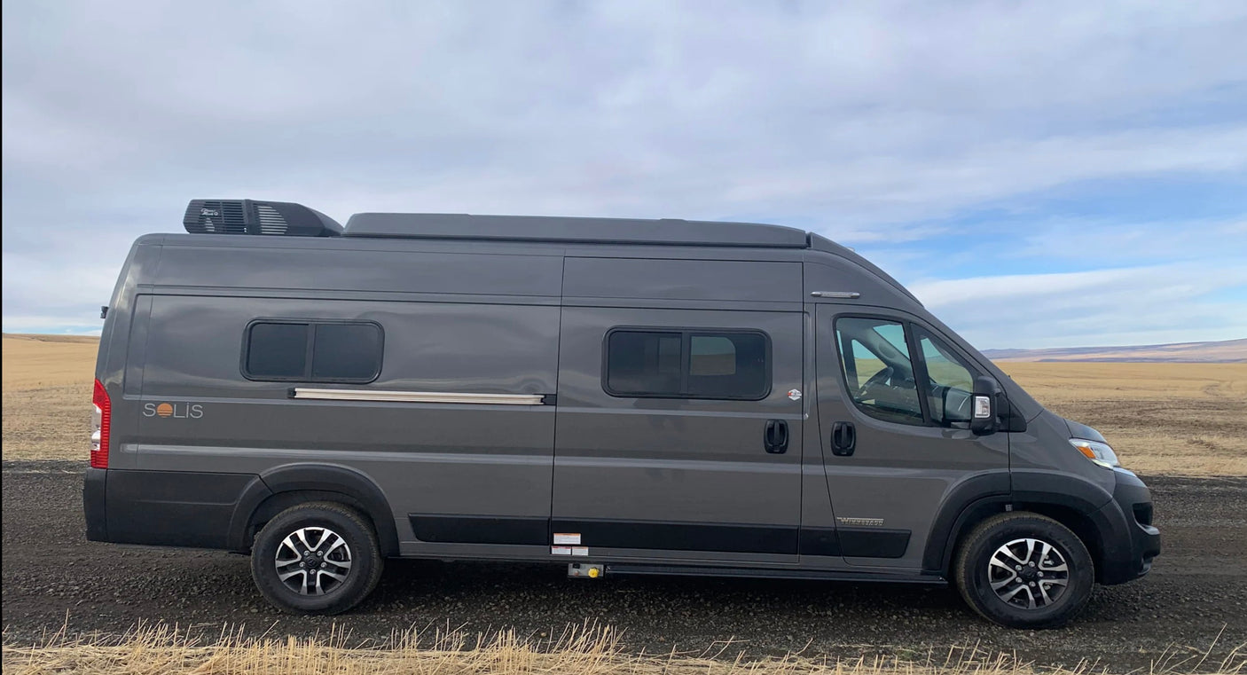 Sleek gray Winnebago Solis campervan, perfect for an rv rental road trip, parked in a vast, dry landscape.