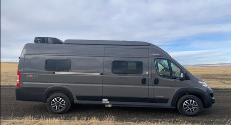 Sleek gray Winnebago Solis campervan, perfect for an rv rental road trip, parked in a vast, dry landscape.