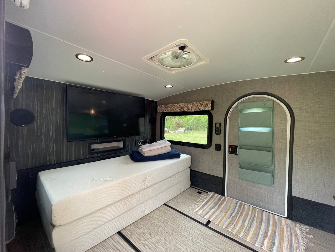 RV rental interior features a large TV, foldable bed, and vent fan, creating a compact yet comfortable living space.