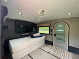 RV rental interior features a large TV, foldable bed, and vent fan, creating a compact yet comfortable living space.