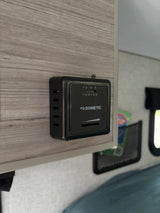 A Dometic thermostat on a wood-grain panel inside an RV rental, providing precise temperature control for climate comfort.