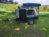 Hiker RV rental: A compact, modern camping trailer with rooftop tent on green grass, perfect for outdoor adventures with scenic views.