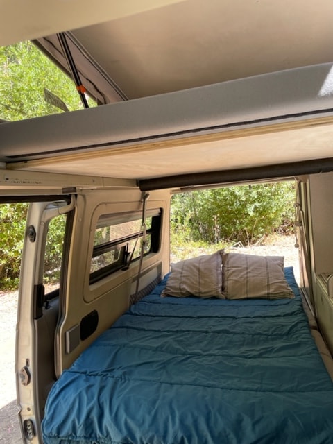  and a passenger seat. Ideal for travel.|White camper van (rv rental) parked by a scenic waterfront with a pier — photo 12