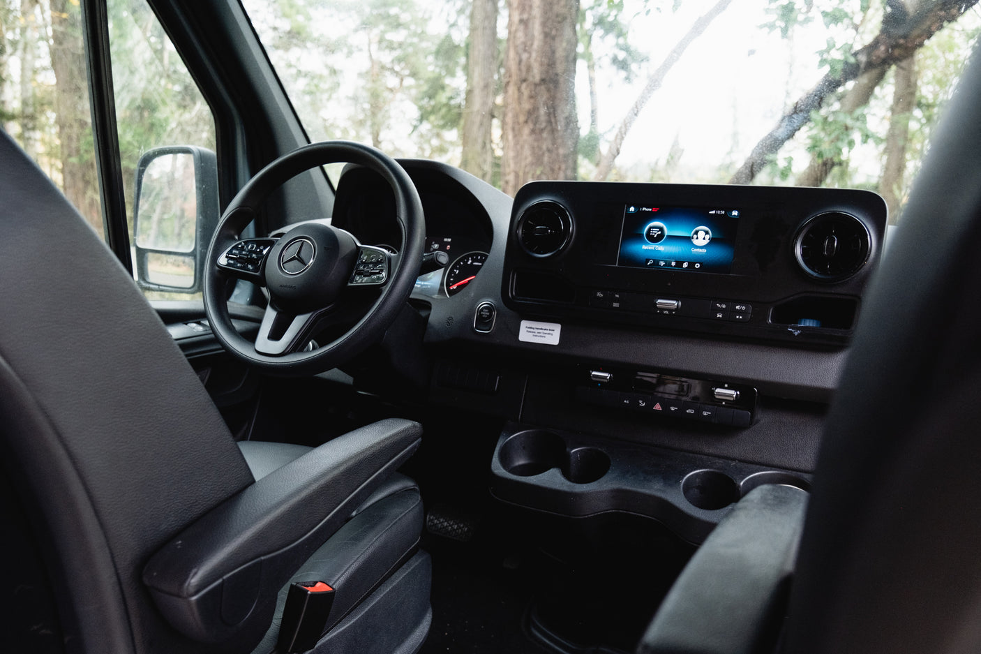 Modern RV rental interior: driver's cockpit with steering wheel, digital dashboard, and infotainment screen. Ready for adventure!